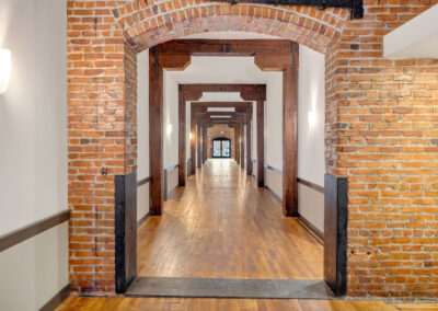 Long hallway interior with brick archway and repeating beams going toward the background