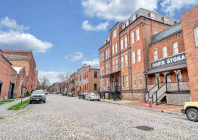 Exterior facades of red brick warehouses lining cobblestone streets. Sign on building says "Davis Storage".