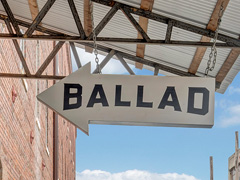 Arrow outside of apartment building with Ballad Brewing logo