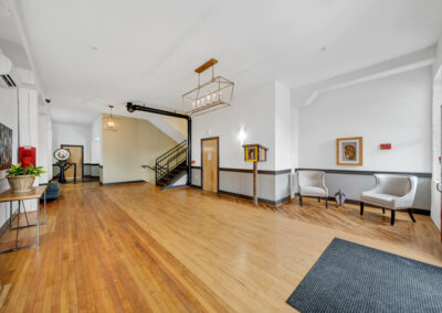 Large open foyer with hardwood floors, seating, and stairwell in the background
