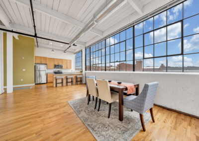 Staged dining room in open floor plan apartment with large industrial windows