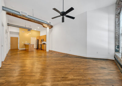Empty apartment space with hardwood floors and exposed brick